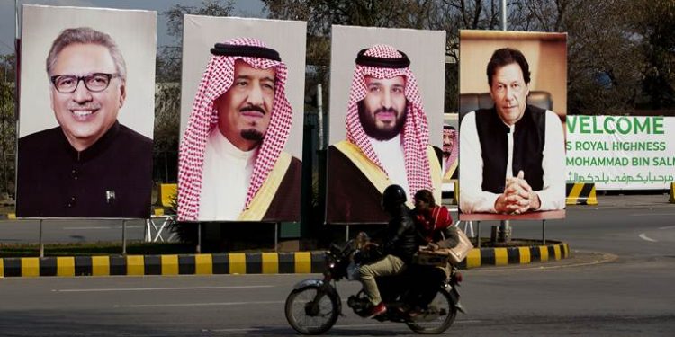 Pakistani riders drive past portraits of Pakistani and Saudi leaders display on the occasion of the visit by Saudi Arabia's Crown Prince to Pakistan, in Islamabad, Pakistan, Friday, Feb. 15, 2019. Pakistan said Wednesday that Crown Prince Mohammed bin Salman will arrive in Islamabad later this week on an official visit that is expected to include the signing of agreements for billions of dollars of investment in Pakistan. (AP Photo/B.K. Bangash)