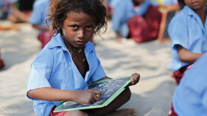 A child whose parents work in a brick kiln attends a class in an open air school at Krishnadevpur village, north of Kolkata, February 11, 2014. REUTERS/Ahmad Masood (INDIA - Tags: EDUCATION SOCIETY) - RTX18LLP