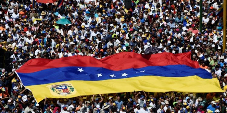Opposition activists display a Venezuelan flag as they pour to the streets to back Venezuelan opposition leader Juan Guaido's calls for early elections, in Caracas February 2, 2019 (AFP)