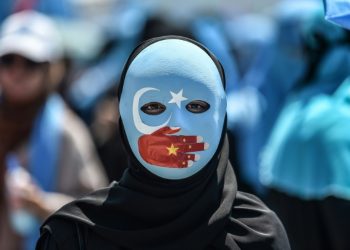 A demonstrator wears a mask with the colors of the East Turkestan flag and a hand depicting the Chinese flag to protest Beijing's treatment of Uighurs outside China's consulate in Istanbul in July 2018 (AFP)