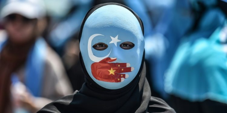 A demonstrator wears a mask with the colors of the East Turkestan flag and a hand depicting the Chinese flag to protest Beijing's treatment of Uighurs outside China's consulate in Istanbul in July 2018 (AFP)