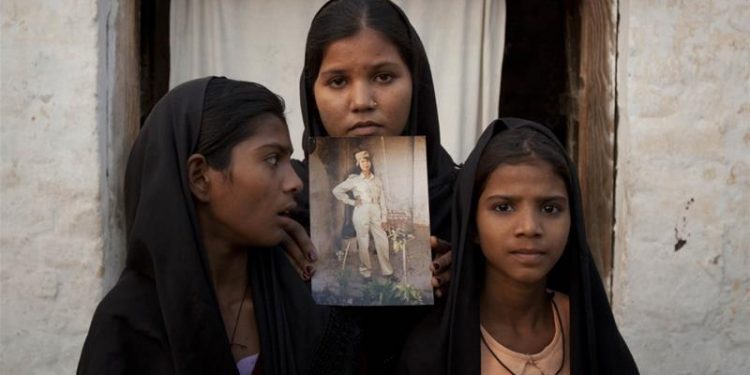 Bibi's daughters with an image of their mother outside their residence in Sheikhupura in Punjab province