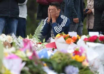 People pay their respects in front of floral tributes for victims of the March 15 mosque attacks, in Christchurch (AFP)