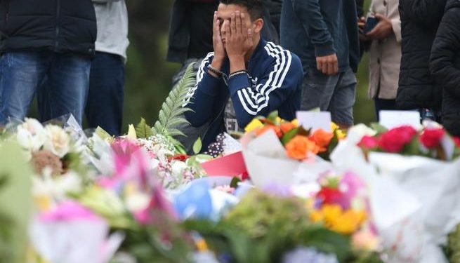 People pay their respects in front of floral tributes for victims of the March 15 mosque attacks, in Christchurch (AFP)