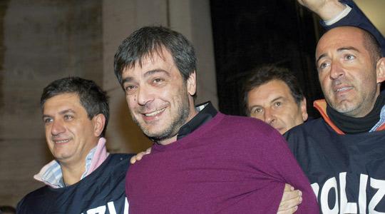 Italian policemen celebrate as they escort Antonio Iovine (centre), one of the most powerful leaders of the Camorra organised crime group, on his arrest after 14 years on the run, yesterday in Naples. (AFP)