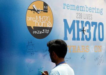 A man writes on a message board for passengers, onboard the missing MH370 flight, during its fifth annual remembrance event in Kuala Lumpur, Malaysia