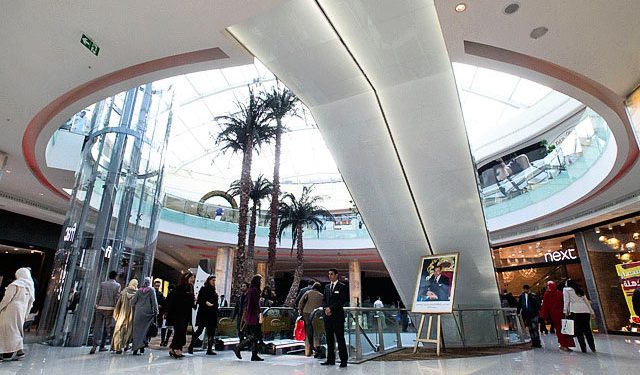 In this photo taken Dec. 16, a poster of Morocco's King Mohammed VI and palm trees are seen underneath an atrium at a new shopping mall in Casablanca, Morocco. Inaugurated by popstar Jennifer Lopez in front of the cream of Moroccan society, Casablanca's first mega mall, complete with two-story-high aquarium, is dripping with glamour and luxury. (AP)