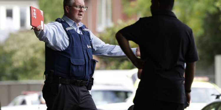 A police officer attempts to move people away from across the road from a mosque in central Christchurch, New Zealand, Friday, March 15, 2019. A witness says a number of people have been killed in a mass shooting at a mosque in the New Zealand city of Christchurch. Police urge people to stay indoors.(AP Photo/Mark Baker)