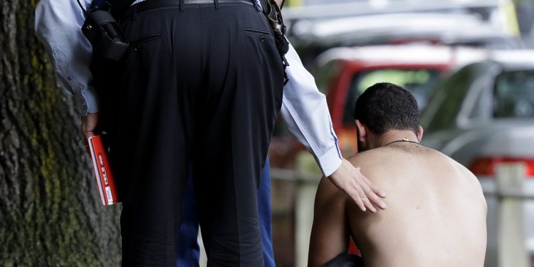 Police console a man outside a mosque in central Christchurch, New Zealand, Friday, March 15, 2019. A witness says a number of people have been killed in a mass shooting at a mosque in the New Zealand city of Christchurch. Police urge people to stay indoors. (AP Photo/Mark Baker)