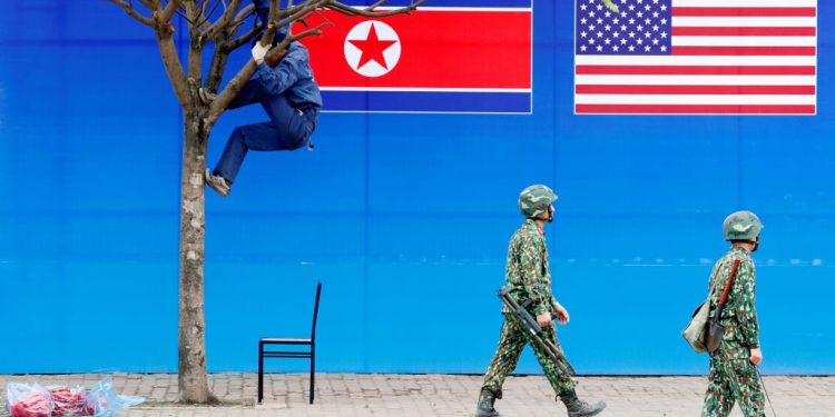 A worker is seen on a tree next to a banner showing North Korean and U.S. flags ahead of the North Korea-U.S. summit in Hanoi, Vietnam, February 25, 2019. (Reuters)