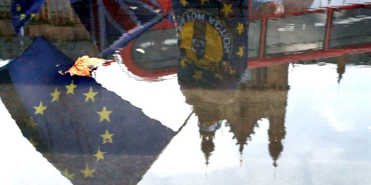 Protestors are reflected in a puddle as they wave European flags to demonstrate against Brexit in front of the Parliament in London, Monday, Dec. 3, 2018. British Prime Minister Theresa May is battling to persuade lawmakers to support the divorce agreement between Britain and the European Union in a Dec. 11 House of Commons vote. Opposition parties say they will vote against it, as do dozens of lawmakers from May's Conservatives. (AP)