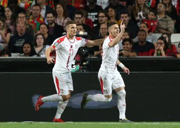 Dusan Tadic (R) wheels away in celebration after putting Serbia ahead against Portugal; home team medical staff attend an injured Cristiano Ronaldo (inset) in Lisbon, Monday