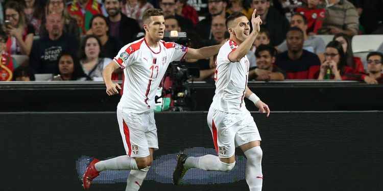 Dusan Tadic (R) wheels away in celebration after putting Serbia ahead against Portugal; home team medical staff attend an injured Cristiano Ronaldo (inset) in Lisbon, Monday