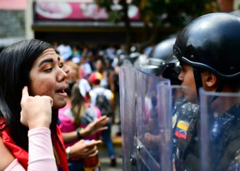 A supporter of opposition leader Juan Guaido speaks with riot police during a protest in Caracas March 9, 2019 (AFP)