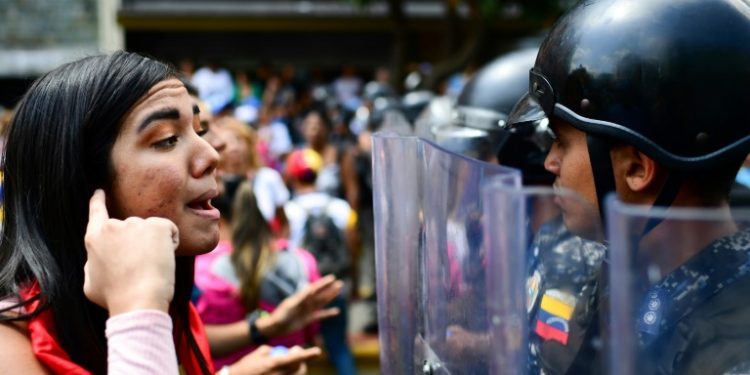 A supporter of opposition leader Juan Guaido speaks with riot police during a protest in Caracas March 9, 2019 (AFP)