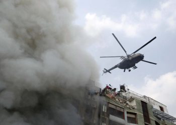 As smoke comes out of the building in Dhaka a helicopter hovers over it to find out trapped people