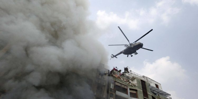 As smoke comes out of the building in Dhaka a helicopter hovers over it to find out trapped people