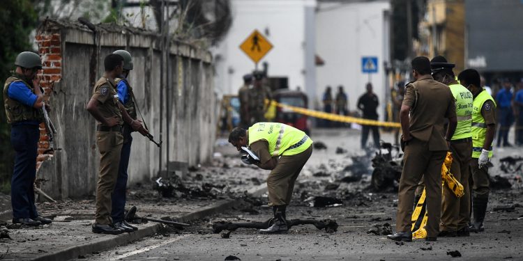 Sri Lankan security personnel inspect the debris of a van after it explodes on Monday near St. Anthony's Shrine in Colombo. Nearly 300 people died and more than 500 others were wounded after Sunday's attacks on churches and hotels.