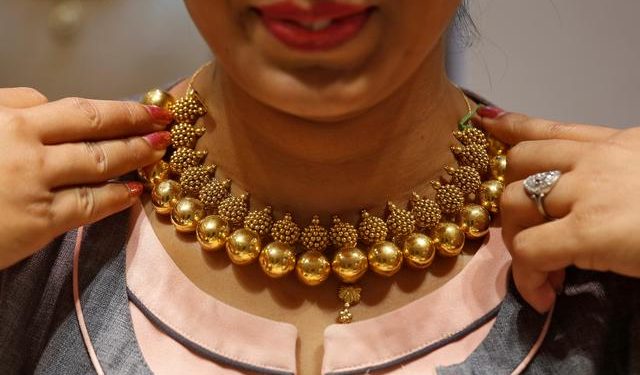 A saleswoman displays a gold necklace to a customer inside a jewellery showroom on the occasion of Akshaya Tritiya, a major gold buying festival, in Mumbai, April 18, 2018. REUTERS/Francis Mascarenhas/Files