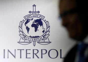 A man passes an Interpol logo during the handing over ceremony of the new premises for Interpol's Global Complex for Innovation, a research and development facility, in Singapore September 30, 2014. REUTERS/Edgar Su/File Photo