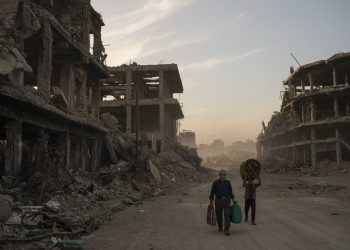 FILE - In this Nov. 15, 2017 file photo, Haider, left, and Abdullah carry belongings they collected from their damaged house to wash before returning to live in the Old City of Mosul, Iraq. A flurry of recent diplomatic activity and high-profile visits to the Iraqi capital, points to a new era of openness as the nation sheds its war image and re-engages with the world. Iraq needs much help and investment to rebuild its cities -- something it can only get from oil- and gas-rich Gulf countries, including Saudi Arabia. (AP Photo/Felipe Dana, File)