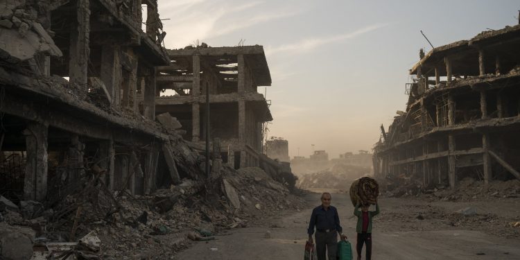 FILE - In this Nov. 15, 2017 file photo, Haider, left, and Abdullah carry belongings they collected from their damaged house to wash before returning to live in the Old City of Mosul, Iraq. A flurry of recent diplomatic activity and high-profile visits to the Iraqi capital, points to a new era of openness as the nation sheds its war image and re-engages with the world. Iraq needs much help and investment to rebuild its cities -- something it can only get from oil- and gas-rich Gulf countries, including Saudi Arabia. (AP Photo/Felipe Dana, File)