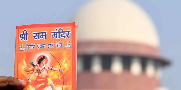 An protester holds a leaflet with the picture of Lord Ram outside the Indian Supreme Court in New Delhi on January 10, 2019, after the hearing in the Ayodhya temple dispute case was further deferred to January 29. - The court is hearing pleas over petitioners demand to build the Ram temple in Ayodhya where a medieval mosque was demolished by Hindu hardliners decades, claiming it was built over an ancient temple dedicated to the birthplace of the deity Ram. It is a deeply polarising project, one that has aggravated deadly fissures between India's Hindu majority and its sizeable Muslim minority. (Photo by Sajjad HUSSAIN / AFP)