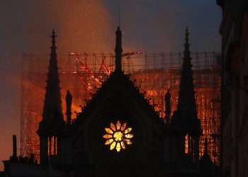 Flames and smoke rise from Notre Dame cathedral as it burns in Paris, Monday, April 15, 2019. Massive plumes of yellow brown smoke is filling the air above Notre Dame Cathedral and ash is falling on tourists and others around the island that marks the center of Paris. (AP Photo/Thibault Camus)