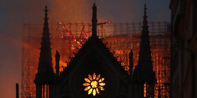 Flames and smoke rise from Notre Dame cathedral as it burns in Paris, Monday, April 15, 2019. Massive plumes of yellow brown smoke is filling the air above Notre Dame Cathedral and ash is falling on tourists and others around the island that marks the center of Paris. (AP Photo/Thibault Camus)