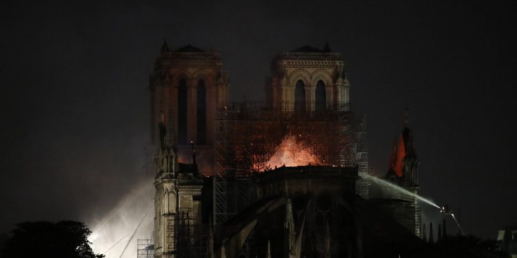 Firefighters tackle the blaze as flames and smoke rise from Notre Dame cathedral as it burns in Paris, Monday, April 15, 2019. Massive plumes of yellow brown smoke is filling the air above Notre Dame Cathedral and ash is falling on tourists and others around the island that marks the center of Paris. (AP Photo/Michel Euler)