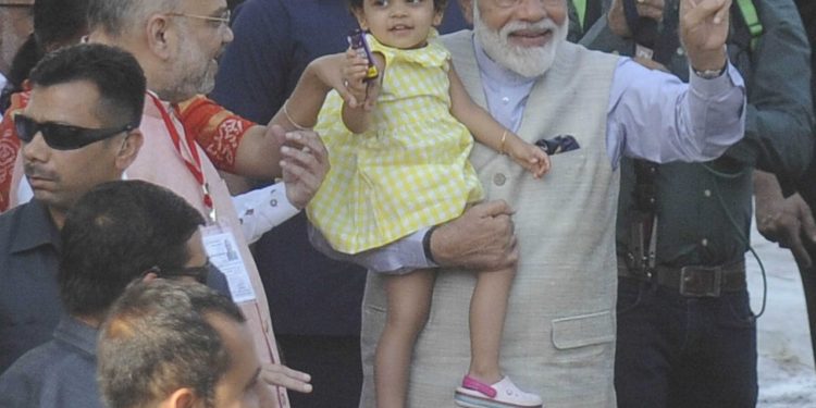 AHMEDABAD, APR 23 (UNI) Prime Minister Narendra Modi showing victory sign outside a polling station, after casting his vote for Lok Sabha election, in Ahmedabad on Tuesday. BJP National president Amit Shah and his granddaughter are also seen in the picture. UNI PHOTO-6U