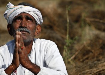 An Indian farmer looks skyward as he sits in his field with wheat crop that was damaged in unseasonal rains and hailstorm at Darbeeji village, in the western Indian state of Rajasthan, Friday, March 20, 2015. Recent rainfall over large parts of northwest and central India has caused widespread damage to standing crops. (AP Photo/Deepak Sharma)