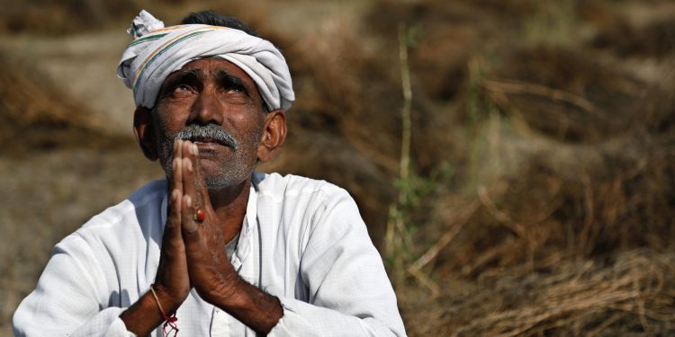 An Indian farmer looks skyward as he sits in his field with wheat crop that was damaged in unseasonal rains and hailstorm at Darbeeji village, in the western Indian state of Rajasthan, Friday, March 20, 2015. Recent rainfall over large parts of northwest and central India has caused widespread damage to standing crops. (AP Photo/Deepak Sharma)