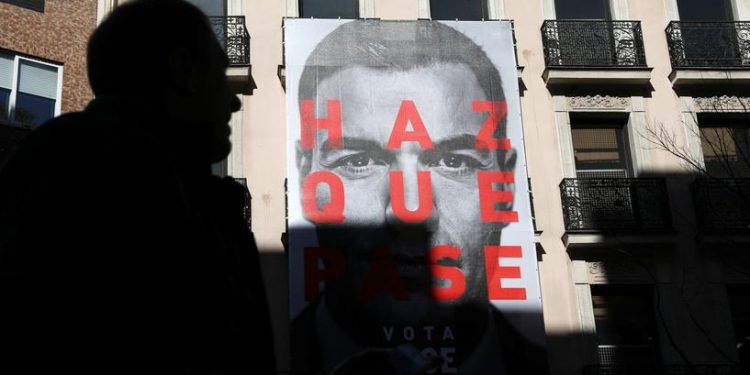 FILE PHOTO - A man walks past an electoral poster of Spain's Socialist (PSOE) leader and current Prime Minister Pedro Sanchez outside the PSOE headquarters in Madrid, Spain, April 12, 2019. REUTERS/Susana Vera