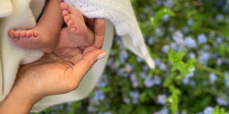 In this undated photo made available on Sunday, May 12, 2019 by @SussexRoyal, Meghan the Duchess of Sussex holds the feet of her baby, Archie Harrison Mountbatten-Windsor. Prince Harry and Meghan, the Duchess of Sussex, have released a photo of their newborn baby to mark Meghan‚Äôs first Mother‚Äôs Day as a mom. The image posted on Instagram shows her hand cradling the feet of Archie Harrison Mountbatten-Windsor, who was born on Monday, against a bed of spring flowers. (@SussexRoyal via AP)