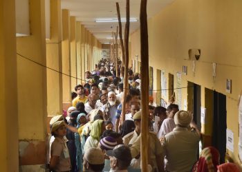 Voters queue up to cast their votes at a polling booth in New Delhi, Sunday