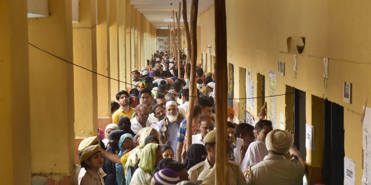 Voters queue up to cast their votes at a polling booth in New Delhi, Sunday