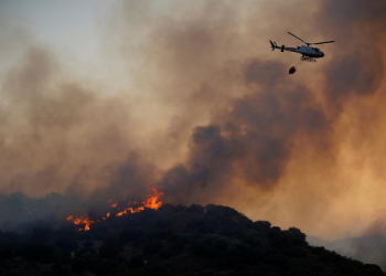 A helicopter flies over a wildfire near the city of Toledo, Spain June 28
