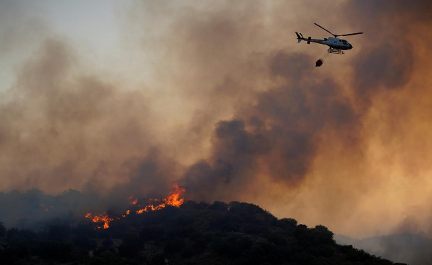 A helicopter flies over a wildfire near the city of Toledo, Spain June 28