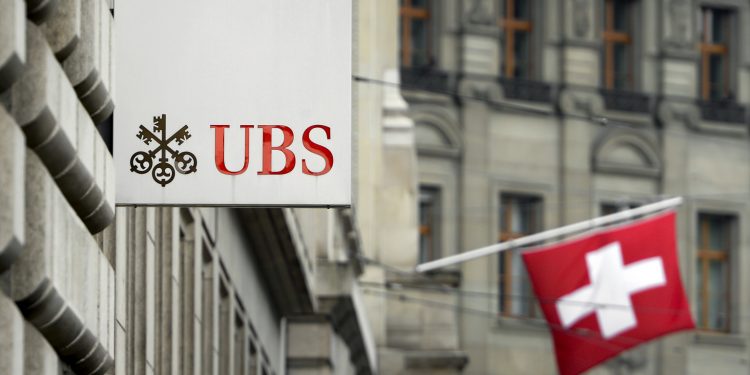 A Swiss flag is seen behind a sign of Swiss bank giant UBS on June 11, 2013 in Basel.  AFP PHOTO / FABRICE COFFRINI        (Photo credit should read FABRICE COFFRINI/AFP/Getty Images)