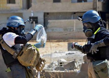 Investigators take samples from sand near a part of a missile that was suspected of carrying Investigators take samples from sand near a part of a missile that was suspected of carrying chemical agents