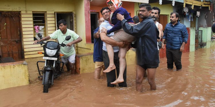 An elderly woman being carried to safety in Kerala's Wayanad district