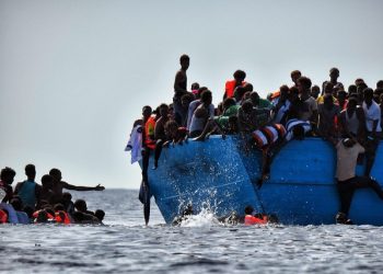 Migrants hang from a boat as they wait to be rescued as they drift in the Mediterranean Sea, some 12 nautical miles north of Libya, on October 4, 2016.
At least 1,800 migrants were rescued off the Libyan coast, the Italian coastguard announced, adding that similar operations were underway around 15 other overloaded vessels. / AFP PHOTO / ARIS MESSINIS