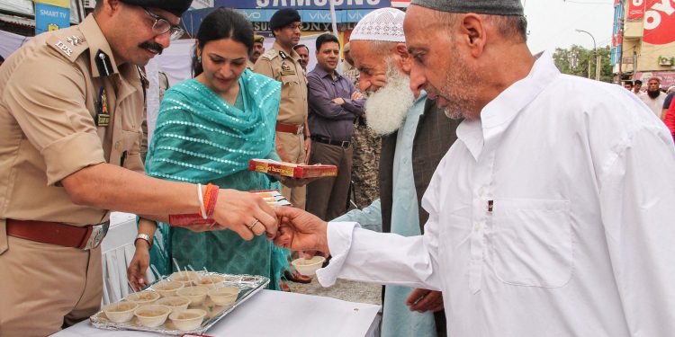 Security personnel offer sweets to residents of Jammu after the prayers Monday