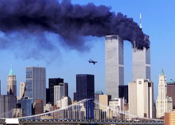 One of the twin towers in New York burning with the second one about to get hit