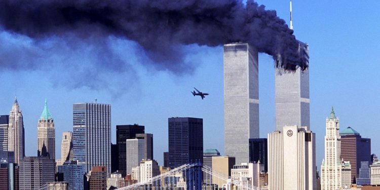 One of the twin towers in New York burning with the second one about to get hit