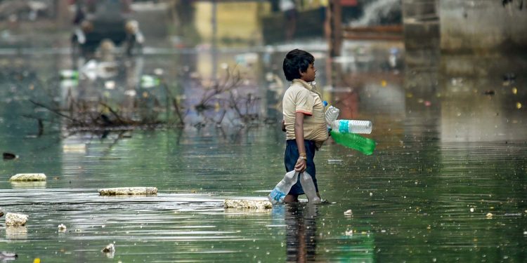 As flood waters recede in Patna a ragpicker collects debris