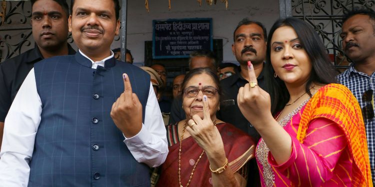 Maharashtra Chief Minister Devendra Fadnavis and his wife Amruta Fadnavi show their fingers marked with indelible ink after casting their votes during Maharashtra Assembly elections, in Nagpur