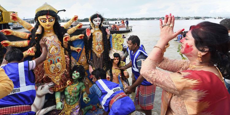 A devotee prays as an idol of Maa Durga is about to be immersed in the Ganges at Kolkata