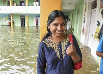 A woman shows her finger marked with indelible ink after casting her vote at a polling station inundated in rain water in Ernakulam